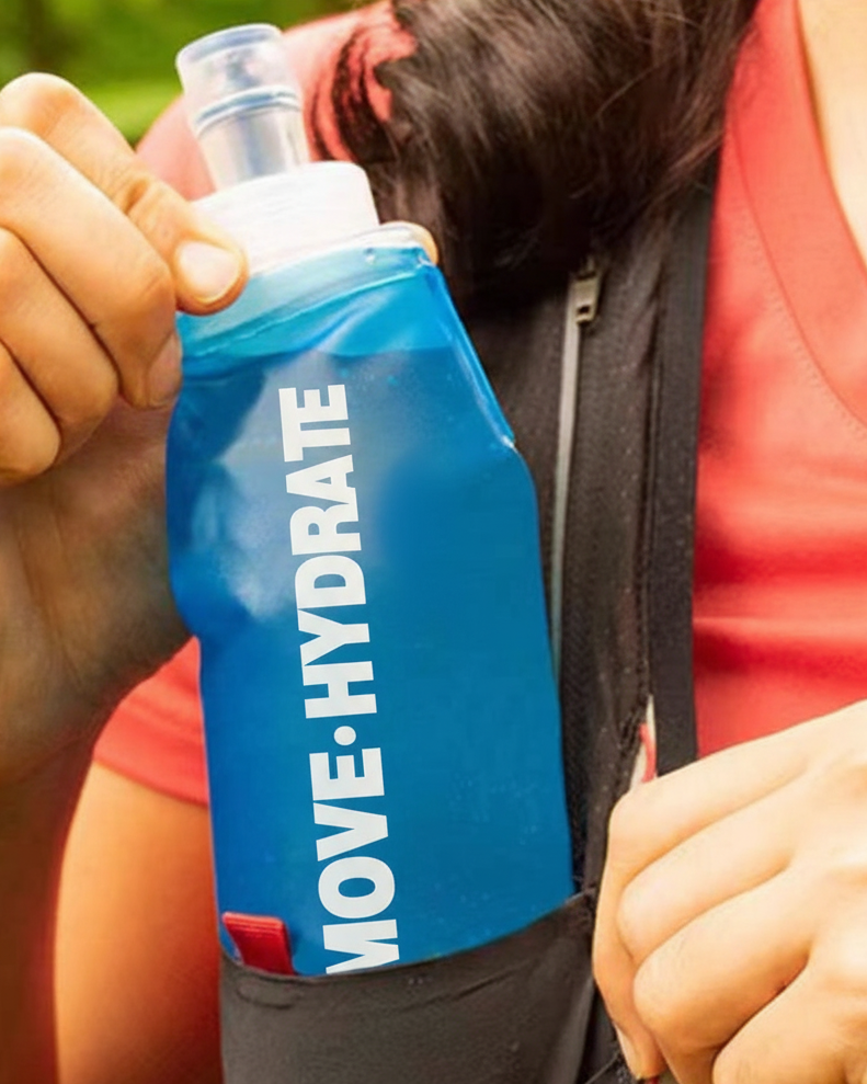 Person holding a blue 'MOVE HYDRATE' water bottle in an outdoor setting